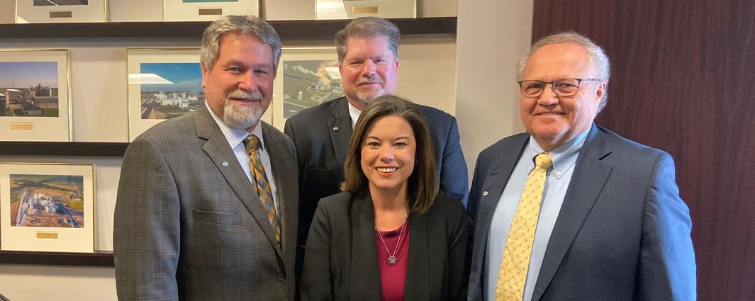 three men and one woman wearing suits